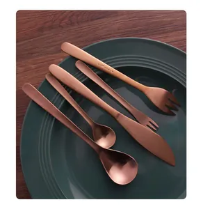 Close-up of rose gold stainless steel cutlery set arranged on a dark green ceramic plate.