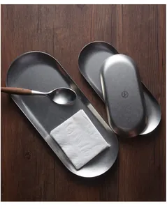 Detailopname van vintage ovale metalen dienbladen op een donkerhouten oppervlak