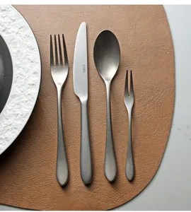 Vintage silver-grey stainless steel cutlery set with matte finish on leather mat.