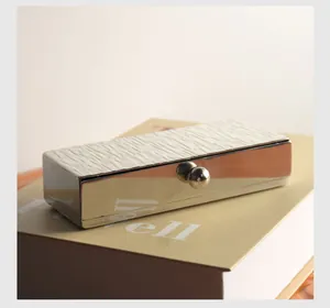 Close-up view of a stainless steel toothpick box with tree bark texture on a book