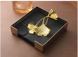 Detailed view of a golden ginkgo leaf weight on a stainless steel napkin holder frame.
