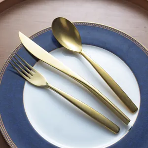 Vintage light luxury gold stainless steel cutlery set with knife fork and spoon on blue plate