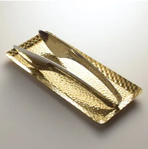 Detailweergave van een gouden gehamerde schaal met zilveren serveertangen