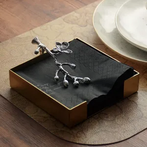 Elegante servilletero cuadrado dorado con una pesa en forma de rama de flor plateada.