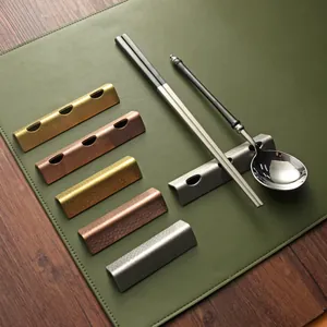 Hammered stainless steel Japanese chopstick rests and spoon holders on a green mat.