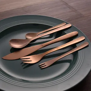 5-piece rose gold stainless steel cutlery set with knife fork and spoon on a teal plate.