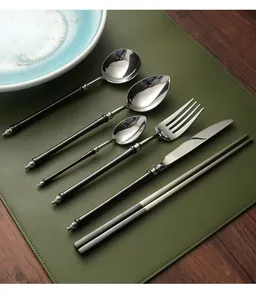Detailview of black and silver retro stainless steel cutlery set on green mat