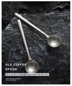 Vintage style stainless steel coffee stirring spoon with matte finish on dark stone.