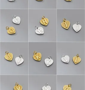 Vista macro detallada de dijes de alfabeto de corazón en plata S925 acabados oro y plata