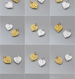 Detalle de los dijes de corazón con iniciales en plata S925 dorada y plateada para joyería DIY.