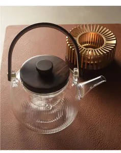 Elegant ribbed glass teapot featuring a wooden lid and a golden candle tea warmer base