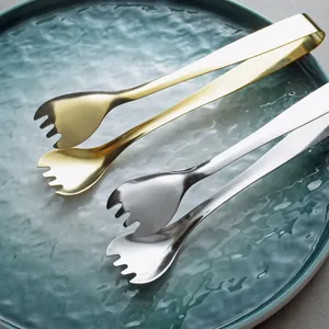 Gold and silver 304 stainless steel food tongs for ice and desserts on a green plate