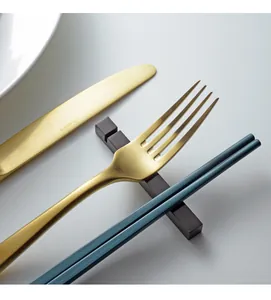 Primer plano de un reposacubiertos minimalista de acero inox con tenedor y palillos