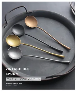 Detail view of four vintage-style stainless steel long-handled spoons on a dark rustic tray