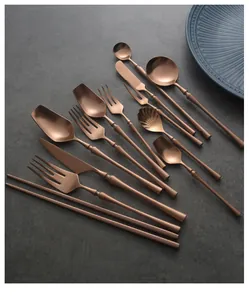 Detailed layout of rose gold stainless steel cutlery set on textured dark background.