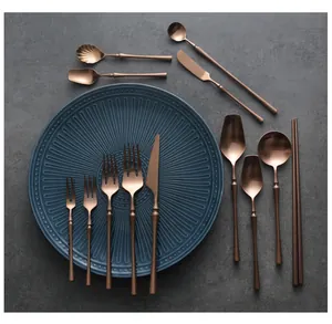 Detailed display of rose gold stainless steel cutlery set with slim handles on blue plate