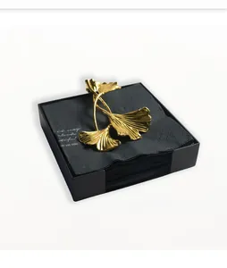 Detail eines goldenen Ginkgoblatt-Serviettengewichts auf schwarzen Papiertüchern