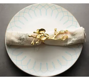 Detalle macro de un servilletero dorado con forma de orquídea en un plato cerámico.