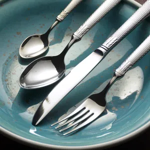 Elegant stainless steel cutlery set with textured handles on a teal ceramic plate