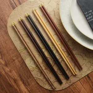 Elegant Chinese wooden chopsticks set with gold-plated metal tips on a textured placemat