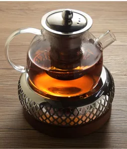 Close-up of glass teapot on a stainless steel candle warmer with wooden base