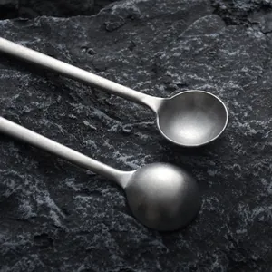 Two vintage Japanese handmade long handle coffee stirring spoons on dark rock background