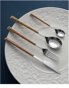 Detail view of stainless steel cutlery set with elegant wood grain handles on a white plate.