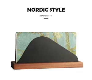 Detail view of a Nordic style napkin holder featuring a solid wood base and black metal frame