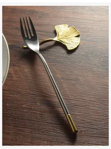 Close-up detail of golden ginkgo leaf cutlery rest with an elegant stainless steel fork