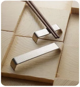 Dettaglio del poggia bacchette in acciaio inox a forma di ponte con finitura martellata
