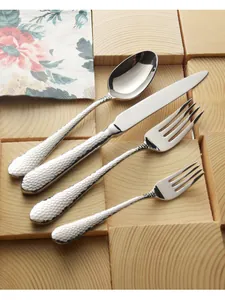Close-up of hammered stainless steel steak knife and forks set on rustic wooden blocks