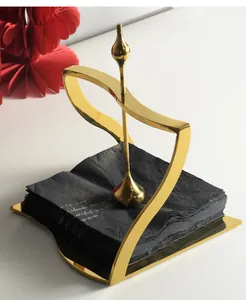 Detail of gold stainless steel napkin holder with weighted arm and black napkins