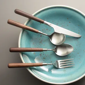 Premium 4-piece stainless steel walnut handle cutlery set displayed on a teal plate