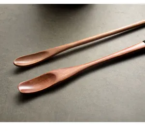 Close-up of long-handled wooden stirring spoons with natural wood grain on grey stone