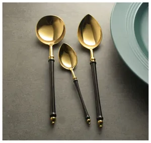 Detailed view of luxury black and gold stainless steel spoons set on a stone surface