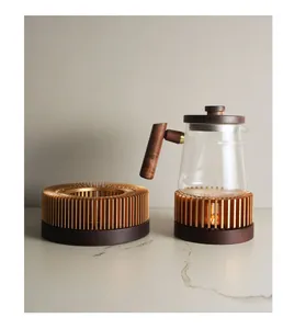 Modern glass teapot with wooden handle on a gold metal and wood candle tea warmer stand