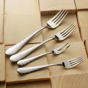 Elegant hammered 304 stainless steel dessert and fruit fork set on a wooden block background
