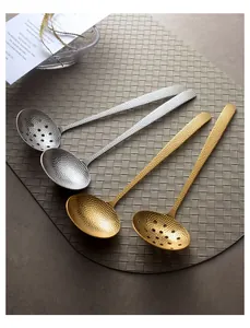 Close-up of hammered 304 stainless steel gold and silver hot pot spoons on a woven mat