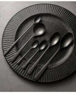 Detailed view of six matte black stainless steel spoons on a textured dark plate