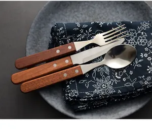Dettaglio del set di posate vintage in acciaio inox con manici in legno rustici sul piatto