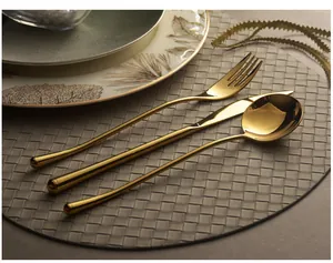 Detailed macro view of golden mirror finish stainless steel cutlery set on a woven mat