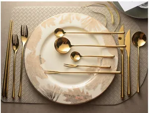 Mirror gold 304 stainless steel cutlery set with steak knives and spoons on a plate