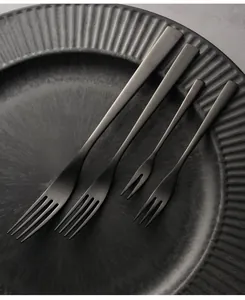 Detail of matte black stainless steel vintage style dinner and fruit forks on plate