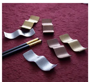 Close-up of hammered stainless steel chopstick rests in gold, silver, and copper
