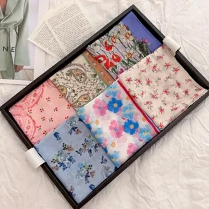 Detailed view of six vintage floral cotton linen handkerchiefs arranged in a black tray