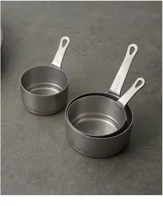 Detailed view of three SUS304 stainless steel measuring cups with a matte sand finish.