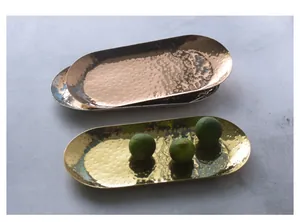 Primo piano di vassoi ovali in acciaio inossidabile martellato nei colori oro, argento e rosa
