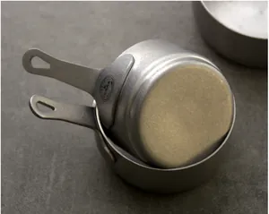 Close-up of retro stainless steel measuring cup with SUS304 engraving and matte finish.