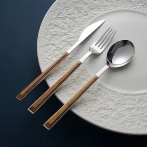 Minimalist 3-piece stainless steel cutlery set with wood-grain handles on white plate