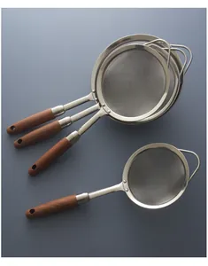 Set of four stainless steel fine mesh strainers with long wooden handles on grey background